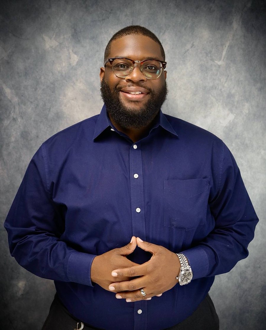 Kortney Darius smiling in a navy dress shirt